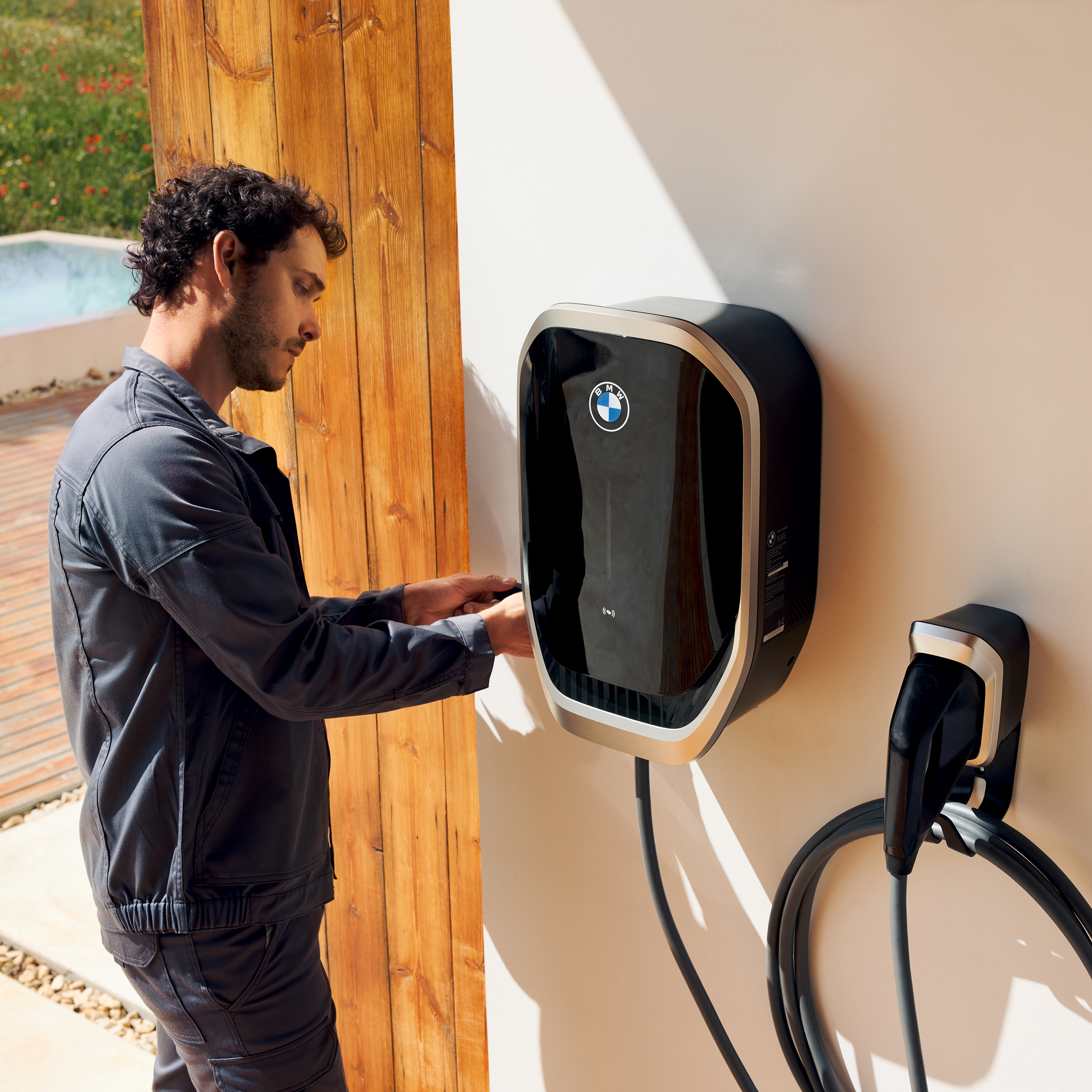 Een persoon sluit een laadkabel aan op een BMW wallbox