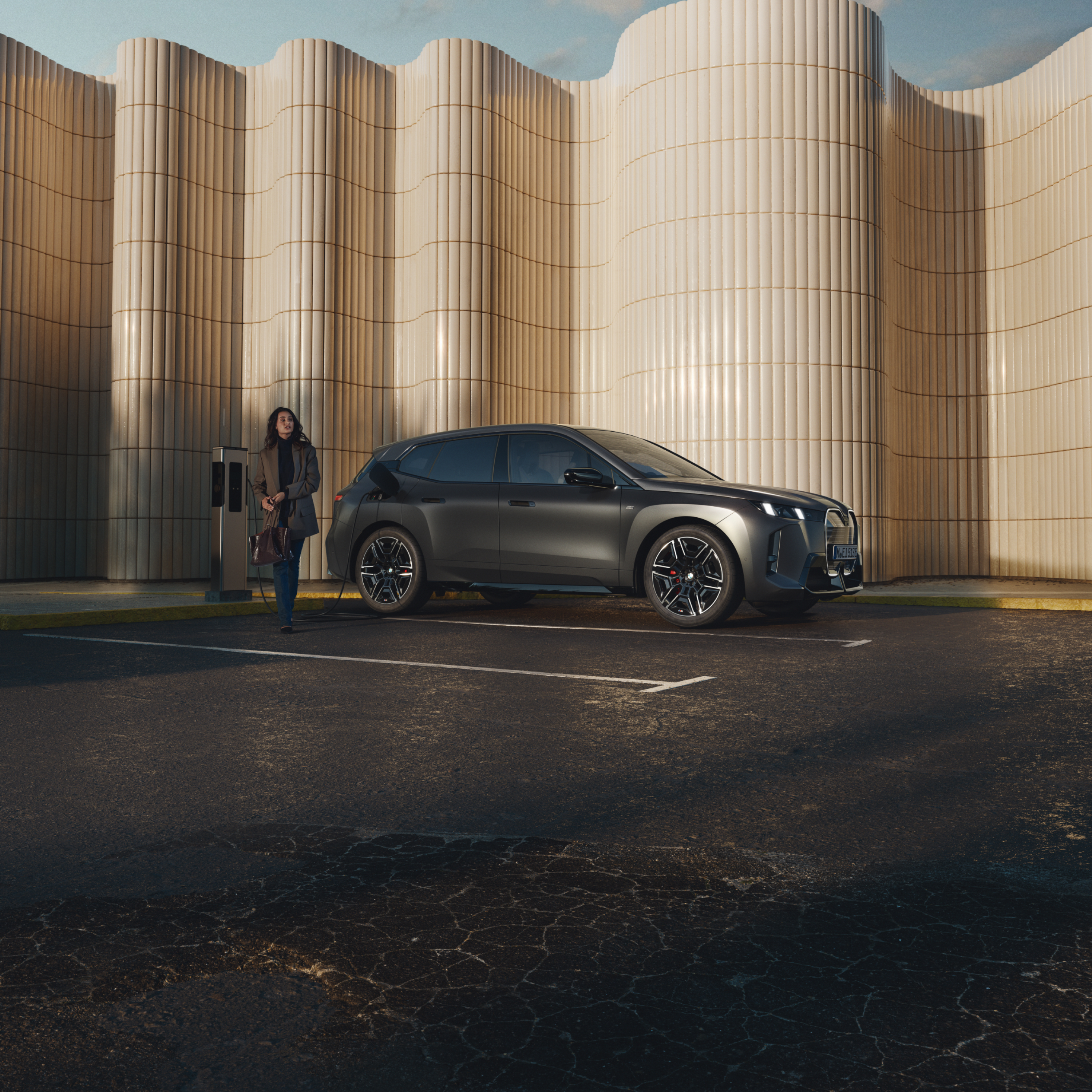 Een persoon leunt tegen een BMW bij een openbare laadpaal langs de weg
