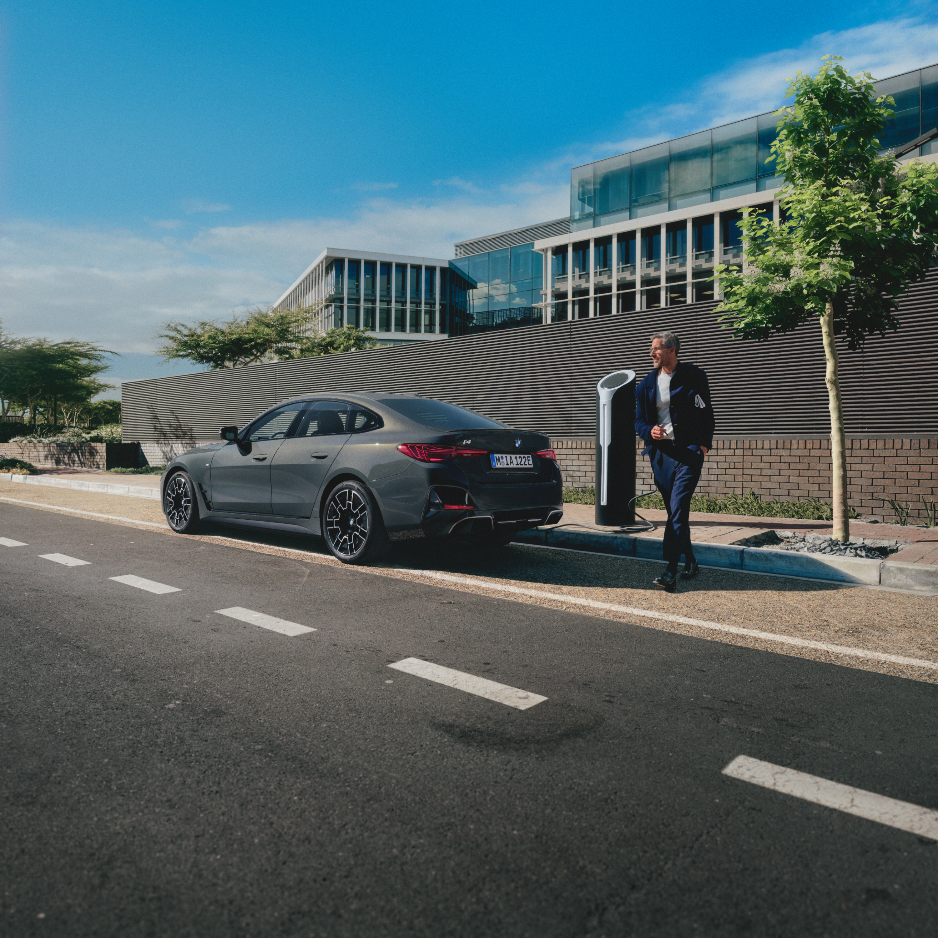 Een persoon staat achter een BMW die aan de kant van de weg wordt opgeladen